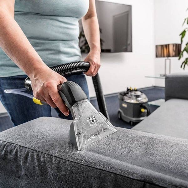 Upholstery extraction tool cleaning a fabric sofa cushion.